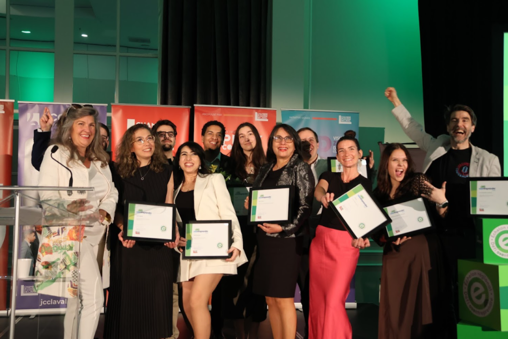 Group of smiling people on stage holding certificates at an awards event, celebrating together.
