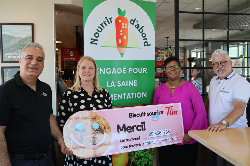 Quatre personnes souriantes présentent un grand chèque en signe de don pour la Fondation Nourrir d'abord, lors d'un événement.