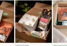 Open gift box with assorted natural skincare and wellness items, including a gray 'MOMENTS' box and pink BKIND packaging on a plant background.
