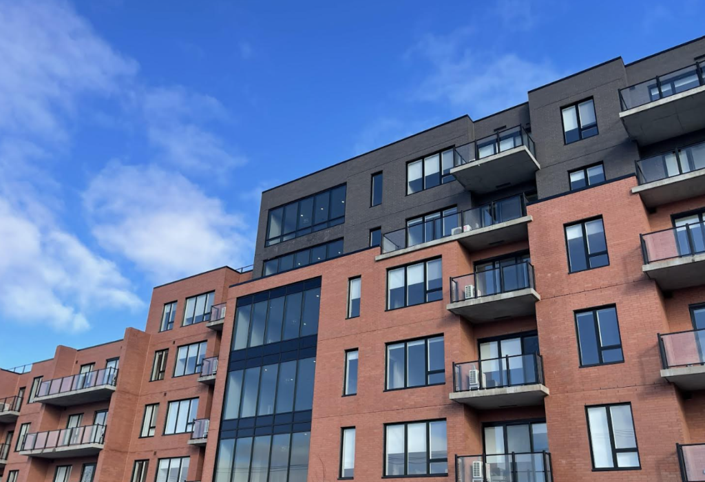 Modern brick apartment building with balconies against a clear blue sky.