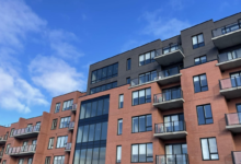 Modern brick apartment building with balconies against a clear blue sky.