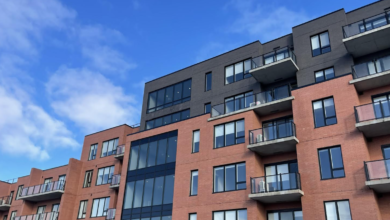 Modern brick apartment building with balconies against a clear blue sky.