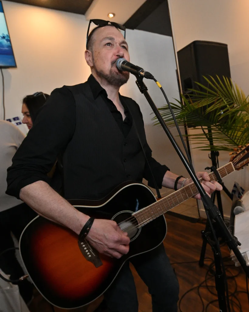 image Média Laval Male guitarist singer performing on stage with sunburst acoustic guitar and microphone stand indoors