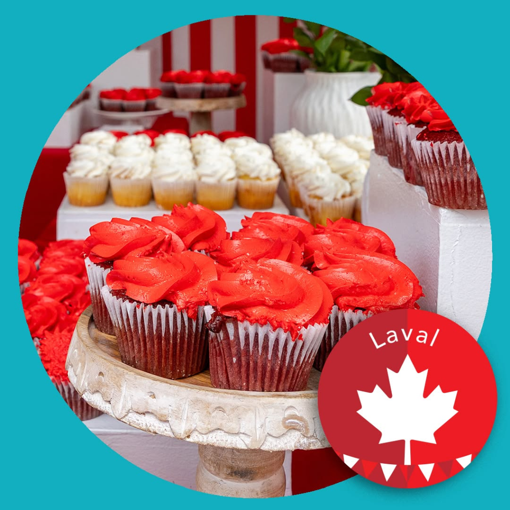 Red-frosted cupcakes on a wooden stand at a bakery display, with white cupcakes in the background and a Laval maple-leaf badge overlay.