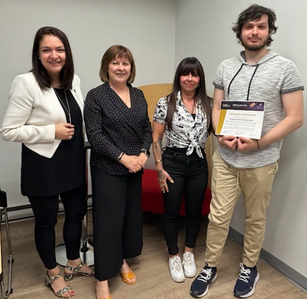image Média Laval Four adults pose together in a room; the man on the right holds a certificate or award.