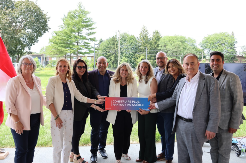 Group of ten professionals outdoors holding a red-to-blue banner that reads 'Construire plus, partout au Québec.'