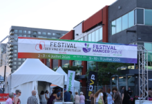 Outdoor festival entrance with a large colorful banner advertising wine, spirits and health-food events in Laval; crowd and white tents beneath.