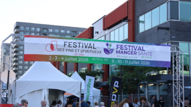 Outdoor festival entrance with a large colorful banner advertising wine, spirits and health-food events in Laval; crowd and white tents beneath.